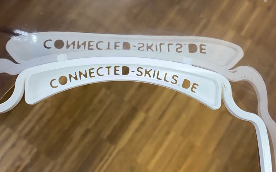 Selbst gefertigtes Gesichtsvisier aus 3D-gedrucktem Rahmen mit dem Aufdruck connected-skills.de